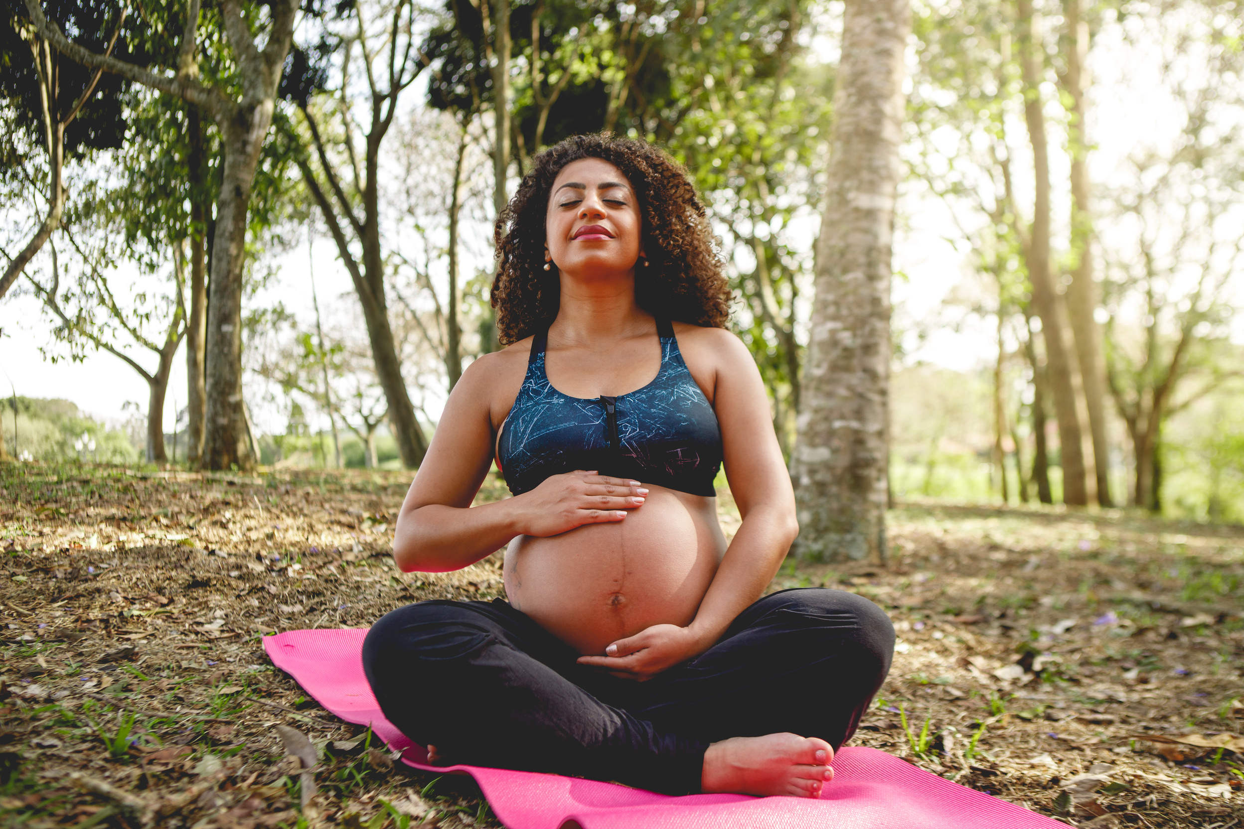 pregnant black woman doing yoga outdoors