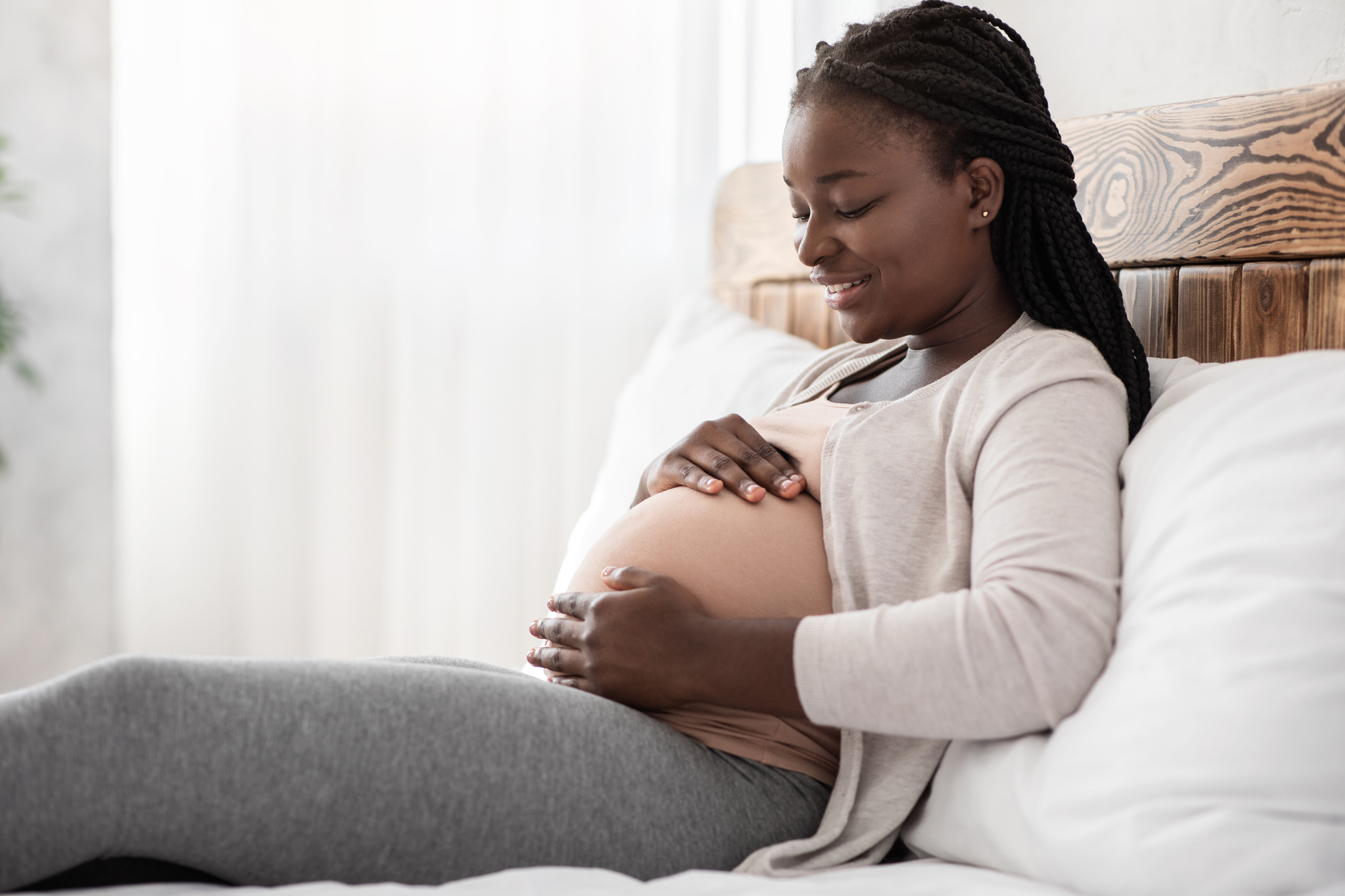 Desirable Pregnancy. Black Pregnant Woman Relaxing On Bed At Home, Touching Belly